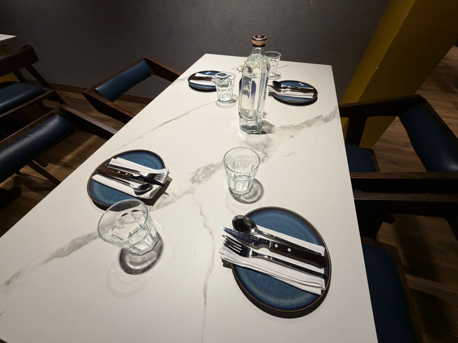 Elegant marble table setup with blue plates and folded linen napkins