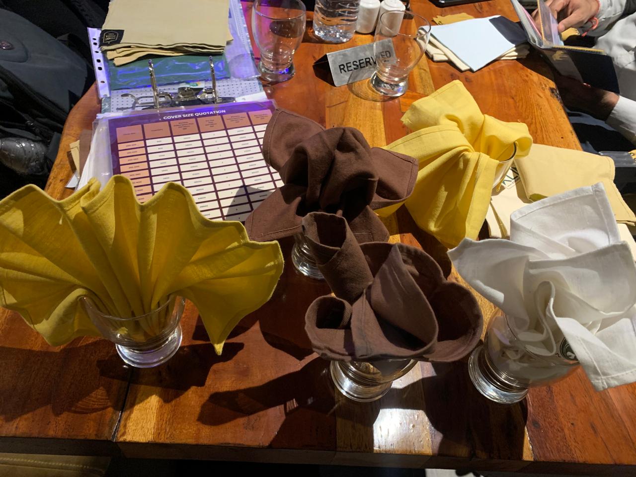 Decorative napkin folds in glassware with quotation chart