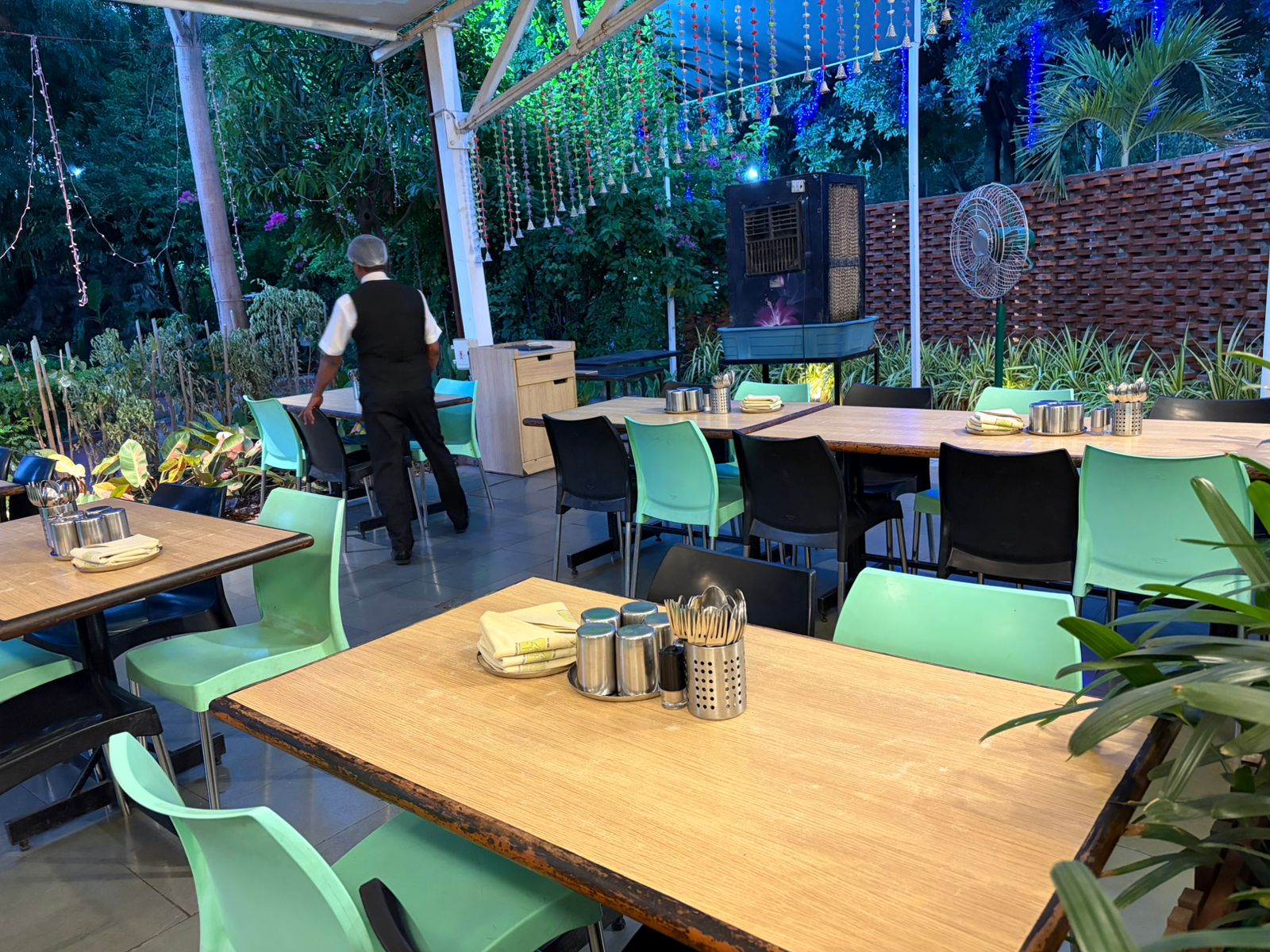 Open-air garden restaurant with green chairs and branded napkin setups