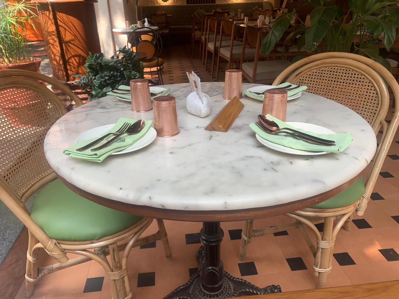 Marble bistro table with green napkin and copper tumblers