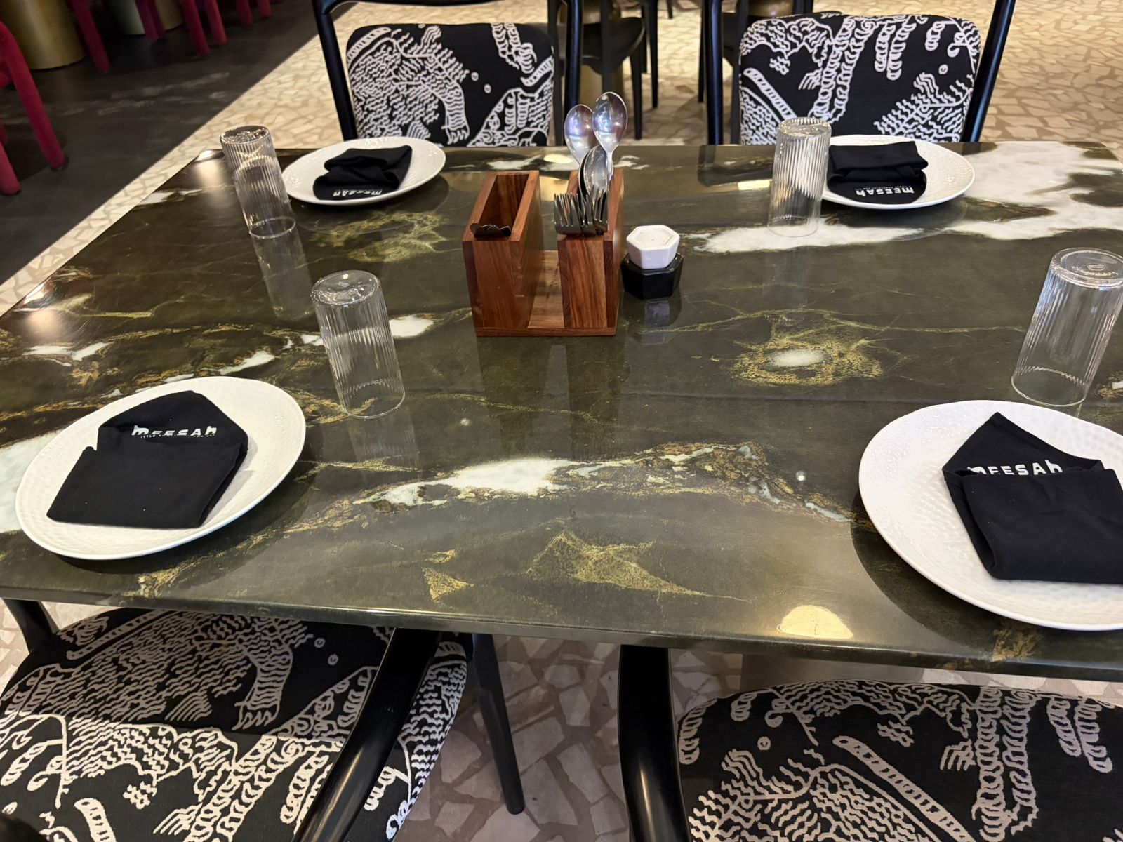 Meesah four-seat marble table with black branded napkins