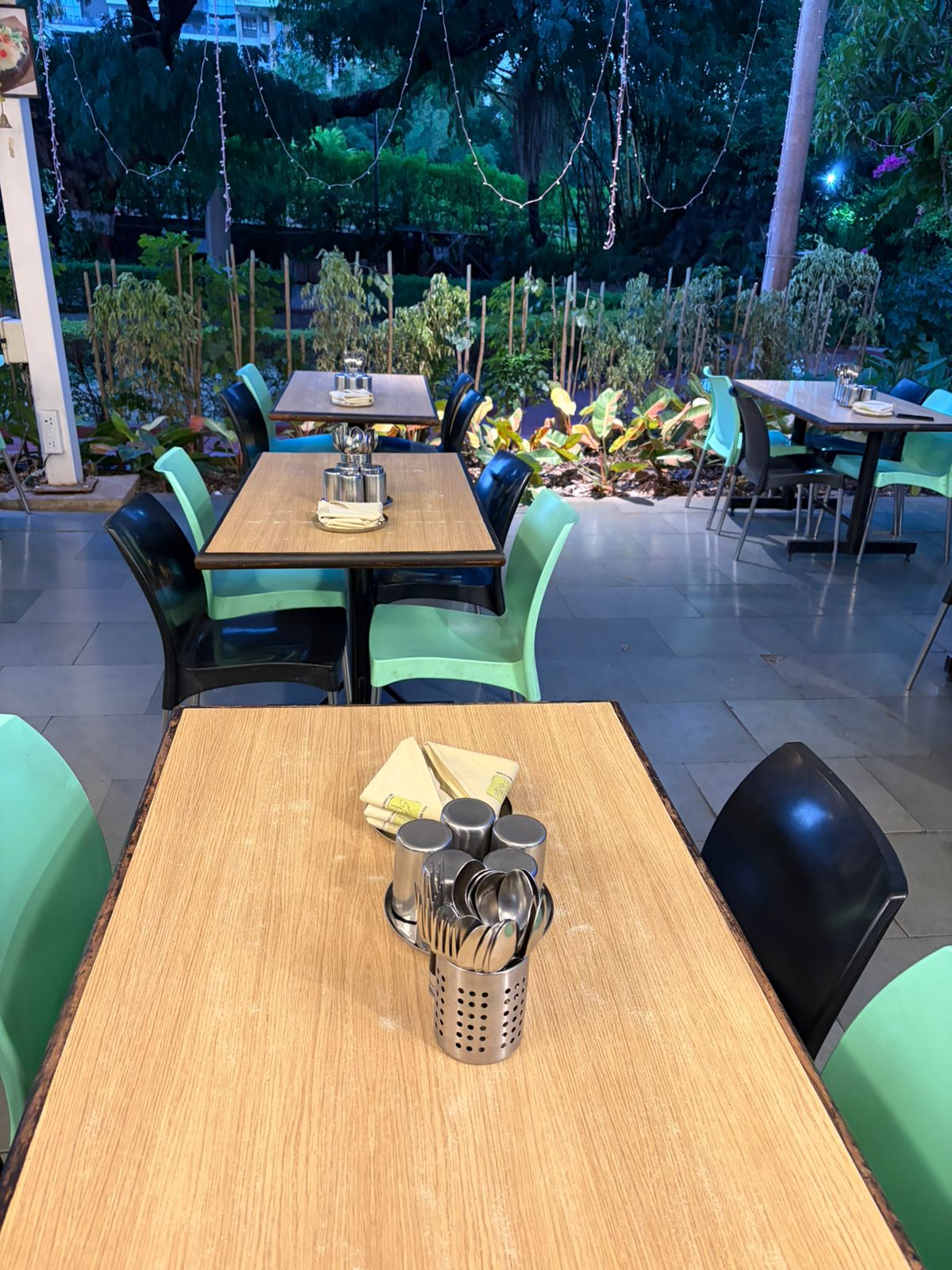 Garden-view café dining with mint green chairs and napkin folds