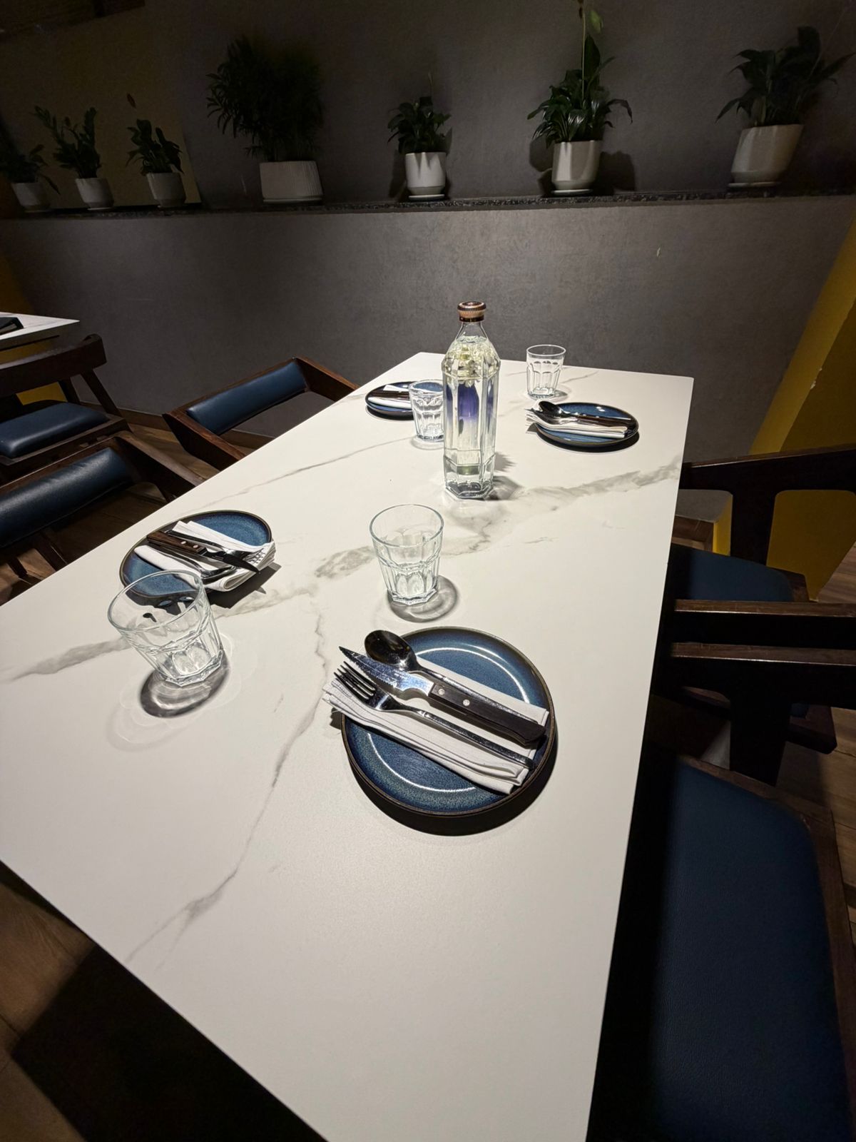 Long marble dining table set with blue plates and linen napkins