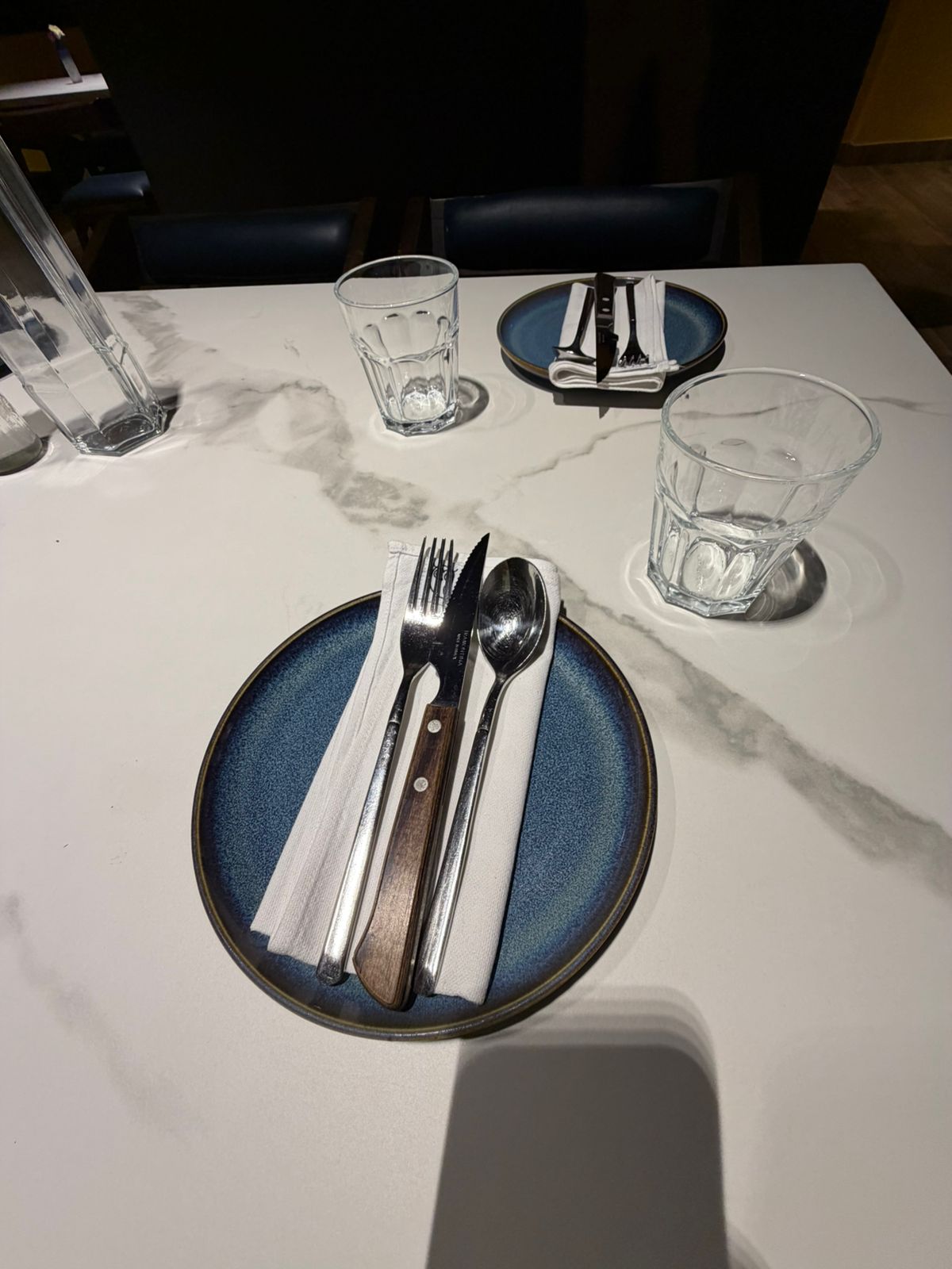 Marble dining table with folded white napkin on blue plate