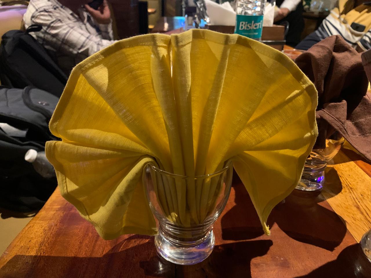 Mustard yellow fan-fold napkin in glassware
